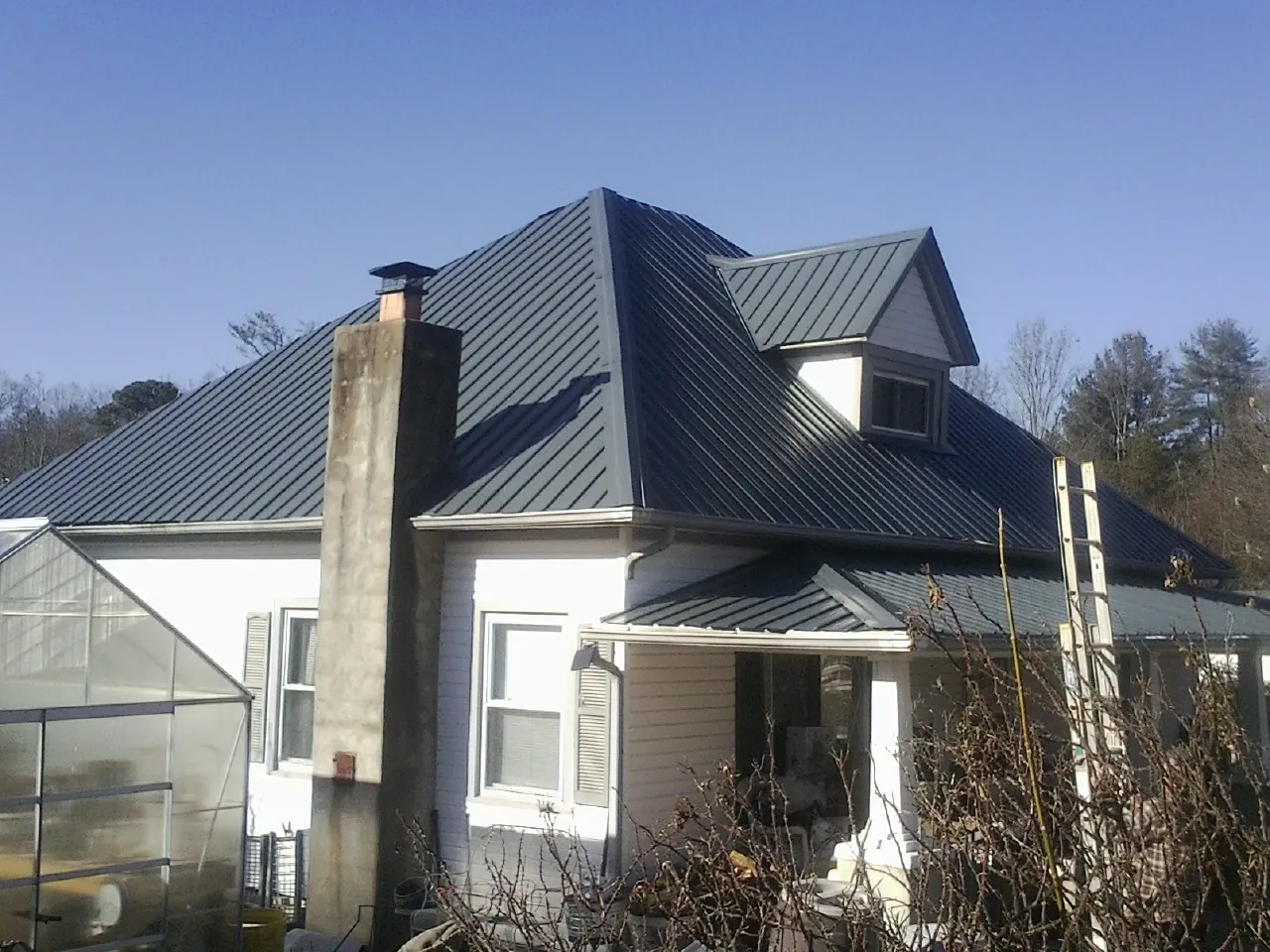 Dark blue standing seam metal roof on a white farmhouse with dormer — Slate & Tile Roof Repair by Roofing Brothers in Minster