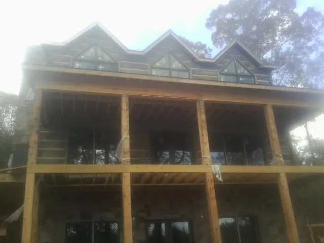 Dormers and porch framing on a large log home under construction — Roof Coating work by our crew in Minster