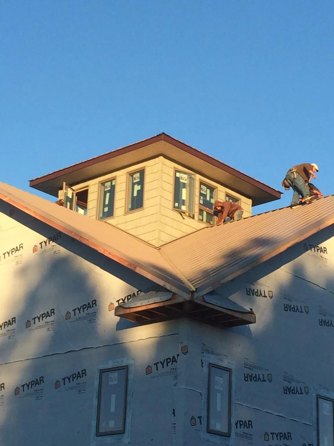 Roofers working around a rooftop cupola on a new metal roof at sunset — Roof Waterproofing in Minster by Roofing Brothers